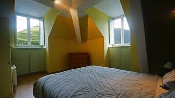 A bedroom with a bed, a dresser, and a window with a view of hills.