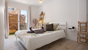 Un dormitorio con cama, una escalera, un ventilador y una estantería con fotografías enmarcadas.