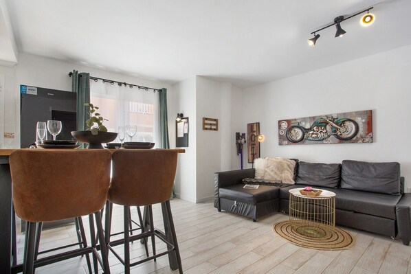 Un salon moderne comprenant un canapé, une table basse et un coin repas avec des chaises et une table.