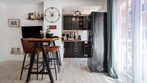 Una cocina moderna con armarios negros, una mesa de comedor de madera y un amplio ventanal con cortinas.