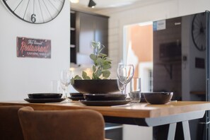 Une table à manger avec des assiettes, des verres et un saladier, une horloge au mur et un panneau indiquant un restaurant.