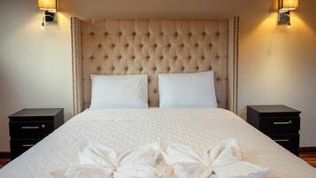 Una habitación de hotel con una cama grande, dos mesitas de noche y lámparas fijadas a la pared.