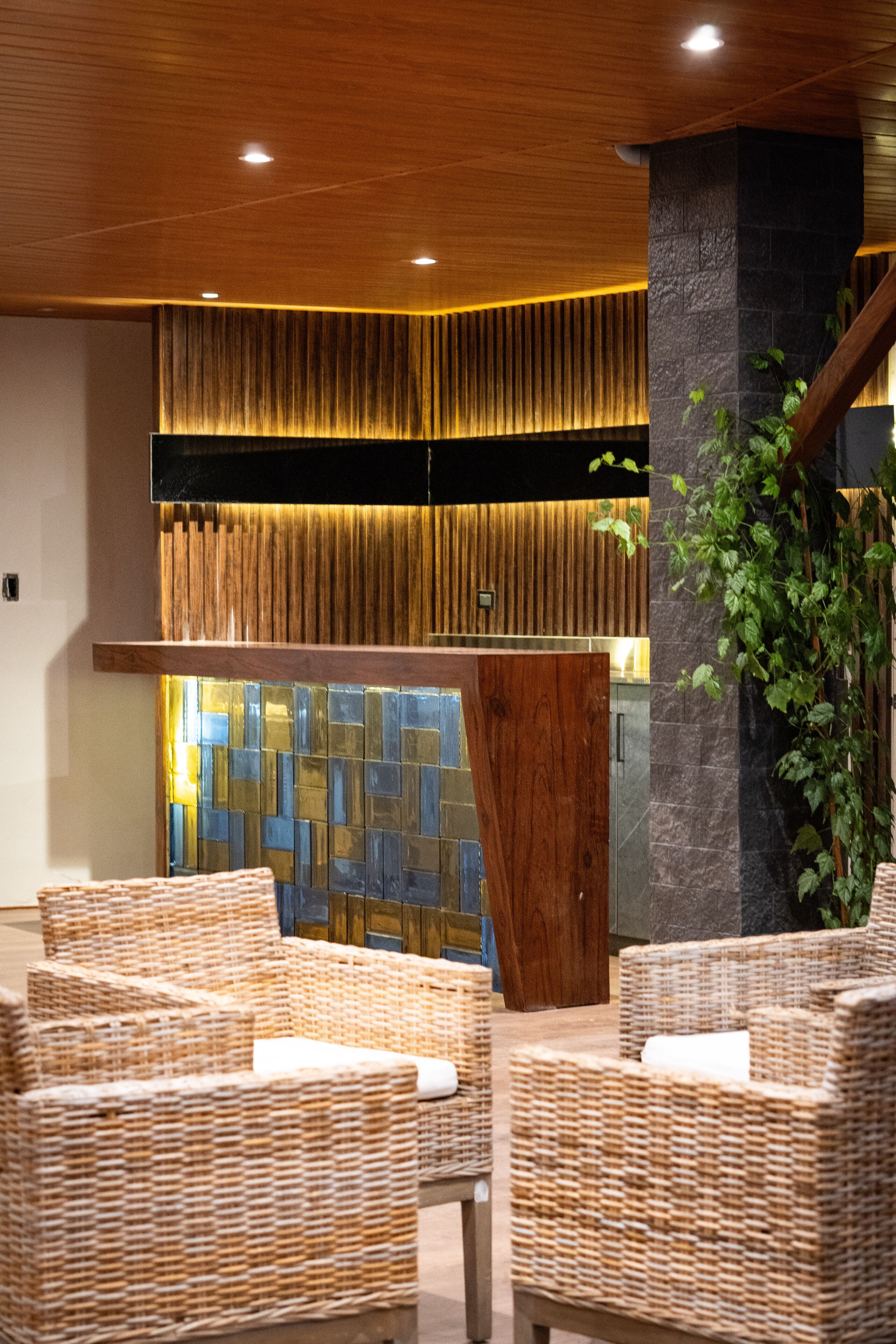 A lobby with wicker chairs, a wooden ceiling, and a stone pillar.