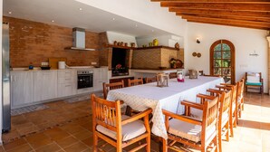 A spacious kitchen with a dining area, wooden ceiling beams, and a brick wall. - Villa "Can Toni" with Mountain View, Private Pool & Wi-Fi (Pollensa)