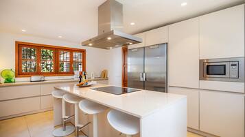 A modern kitchen with a central island, stainless steel appliances, and a window with wooden frames.