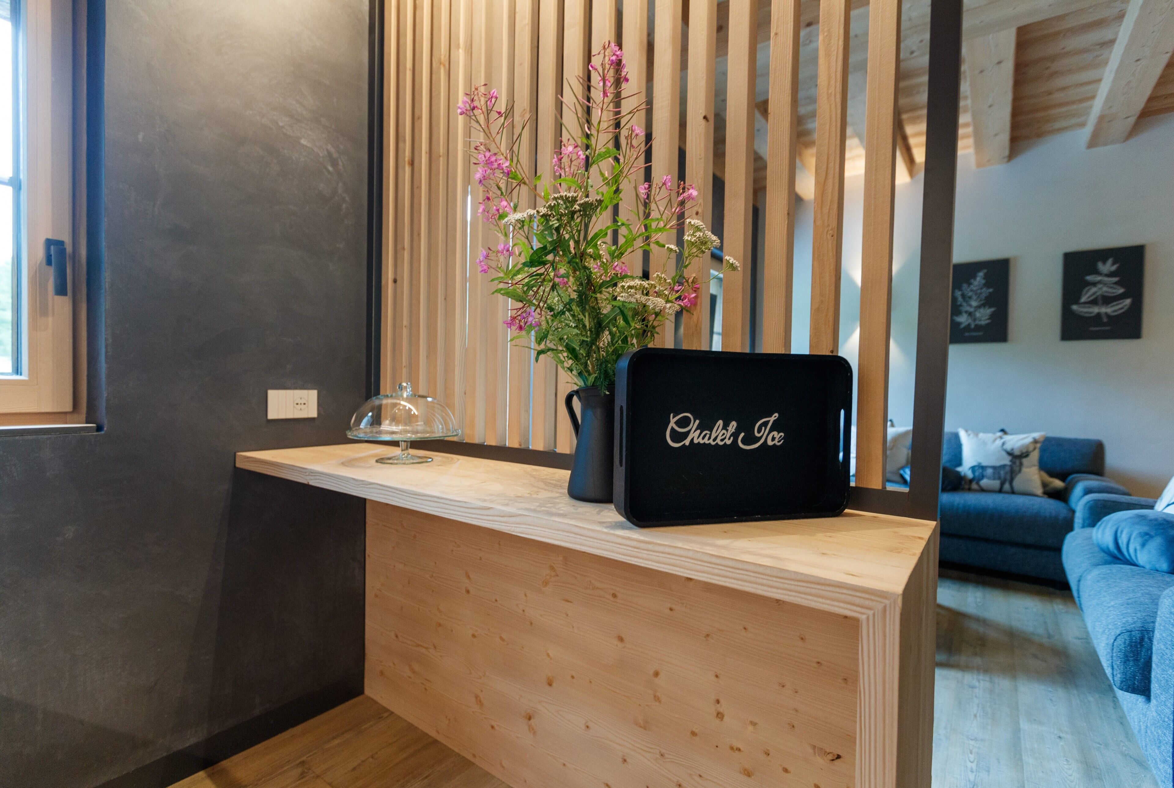 Un comptoir d’accueil orné d’un vase de fleurs, avec une enseigne noire et un comptoir en bois.