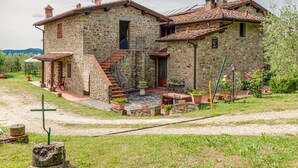 Un edificio de piedra con escaleras, asientos exteriores y un jardín.