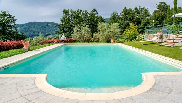 A rectangular swimming pool with a curved edge, surrounded by a stone deck. - Apartment 'Il Cerro Basic Per Due' with Shared Pool and Shared Garden (Pelago)