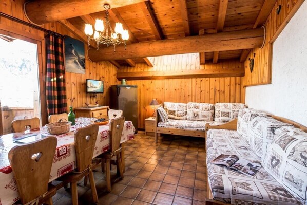Un intérieur en bois comprenant une table à manger, des chaises, un canapé et un téléviseur.