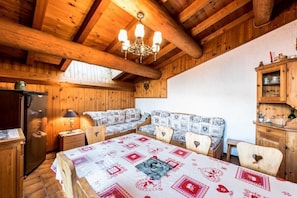 A cozy wooden room with a dining table, chairs, a sofa, a chandelier, and a cabinet. - Apartment "Le Rhododendron" with Mountain Views, Shared Garden & Wi-Fi (La Plagne-Tarentaise)