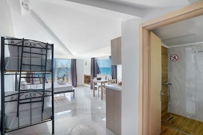 A modern hotel room with a bunk bed, a dining area, a shower, and a view of the sea. - Studio Apartment 'Iguana 18' with Sea View, Wi-Fi and Air Conditioning (Preveza)
