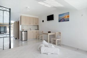 A modern kitchen with wooden cabinets, a stainless steel refrigerator, and a dining area with chairs and a table.