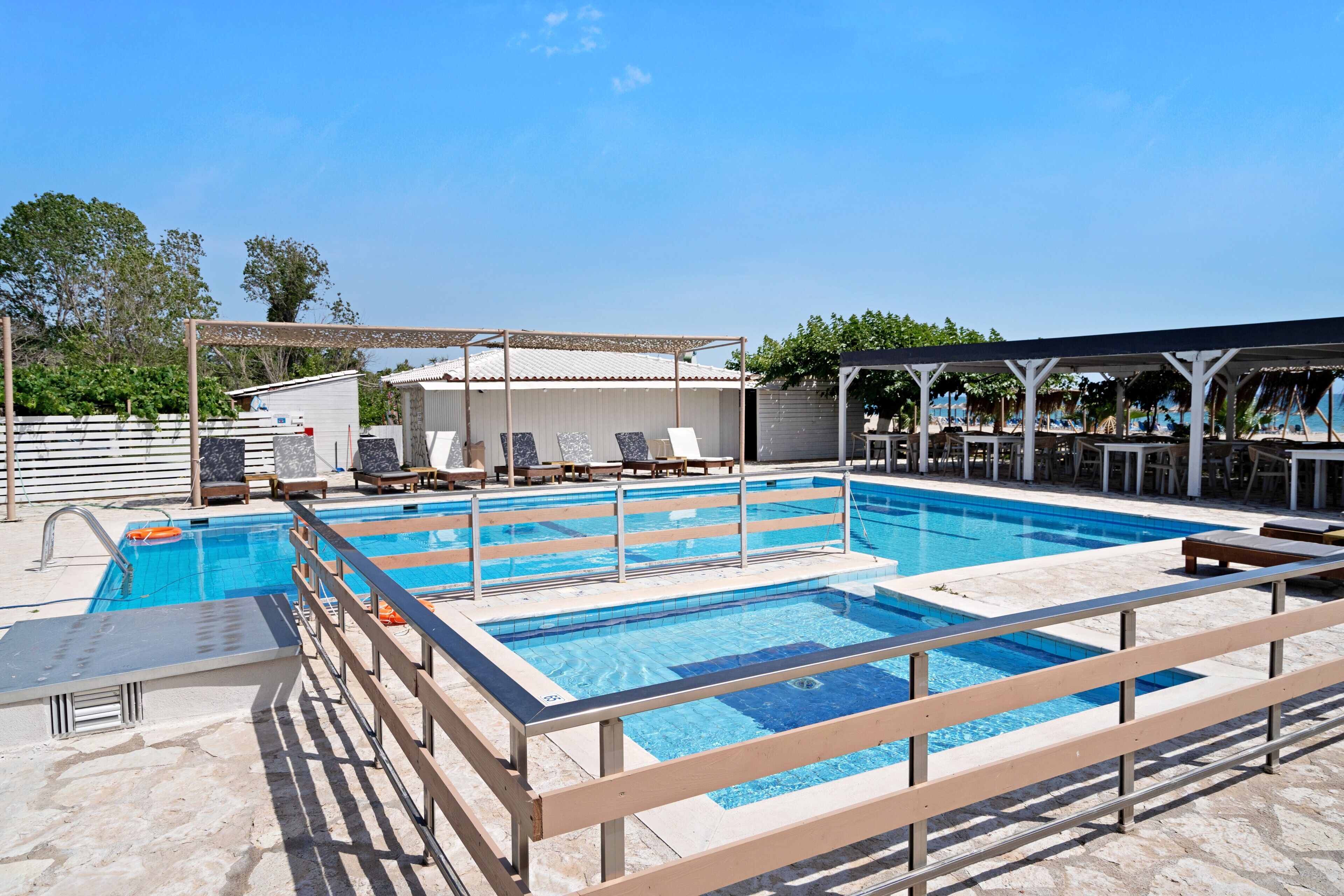 A swimming pool with multiple lanes, sun loungers, and a covered seating area.