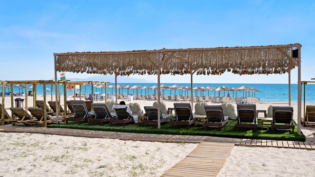 A beachside lounge area with wooden loungers, a thatched canopy, and a wooden deck leading to the beach. - Studio Apartment 'Iguana 6' with Sea View, Wi-Fi and Air Conditioning (Preveza)