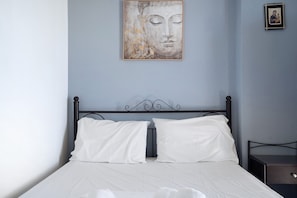 A bed with white bedding, a headboard, and a nightstand with a drawer.