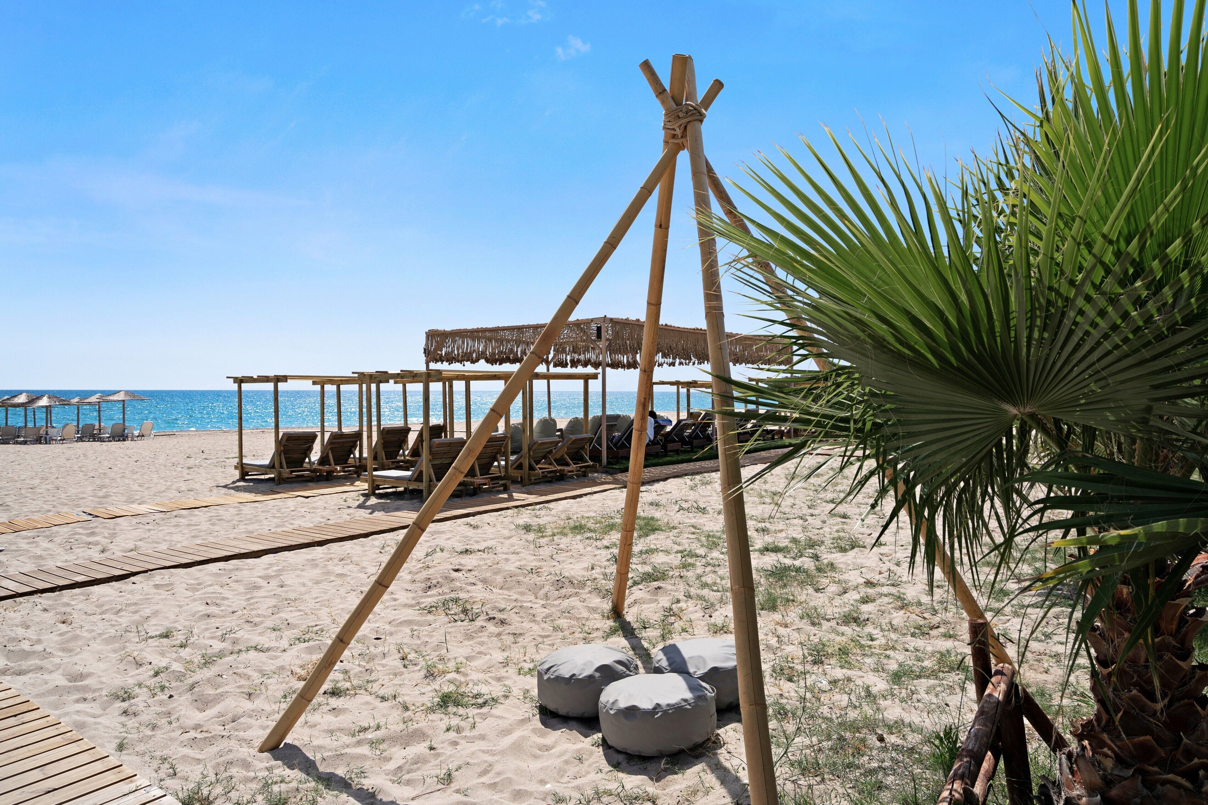 Une plage avec des structures en bois, des chaises longues et un palmier.