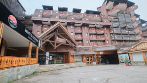 Un edificio de varios pisos con balcones, fachada de madera y un letrero que dice 'Vente & Location Rental & Services'.