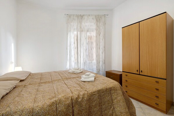 A bedroom with a bed, a wardrobe, and a window with curtains. - Apartment 'Casa Rosa' with Private Terrace and Wi-Fi (Loano)