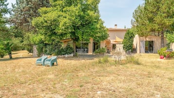 A property with a patio area, outdoor seating, and a building with a tiled roof.