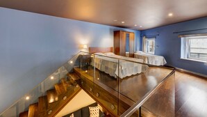 Une chambre à coucher avec un lit, une armoire, une fenêtre et un escalier.