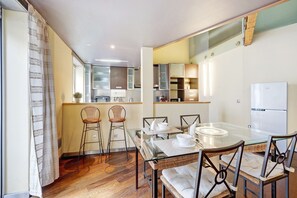 A modern kitchen with a dining area, including a glass table and wicker chairs.