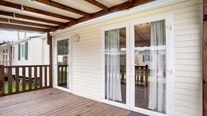 Una terraza cubierta de madera con una puerta corrediza de vidrio que da a un patio cubierto.