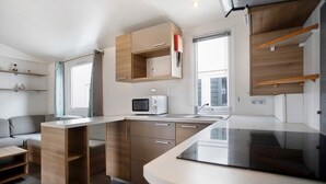 A compact kitchen with a microwave, wooden cabinets, and a built-in sink.