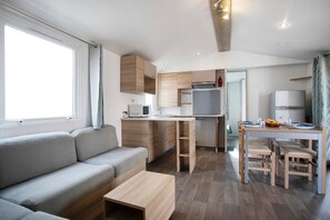 Un ambiente compatto con angolo cottura, divano, tavolo da pranzo e piccola cucina.