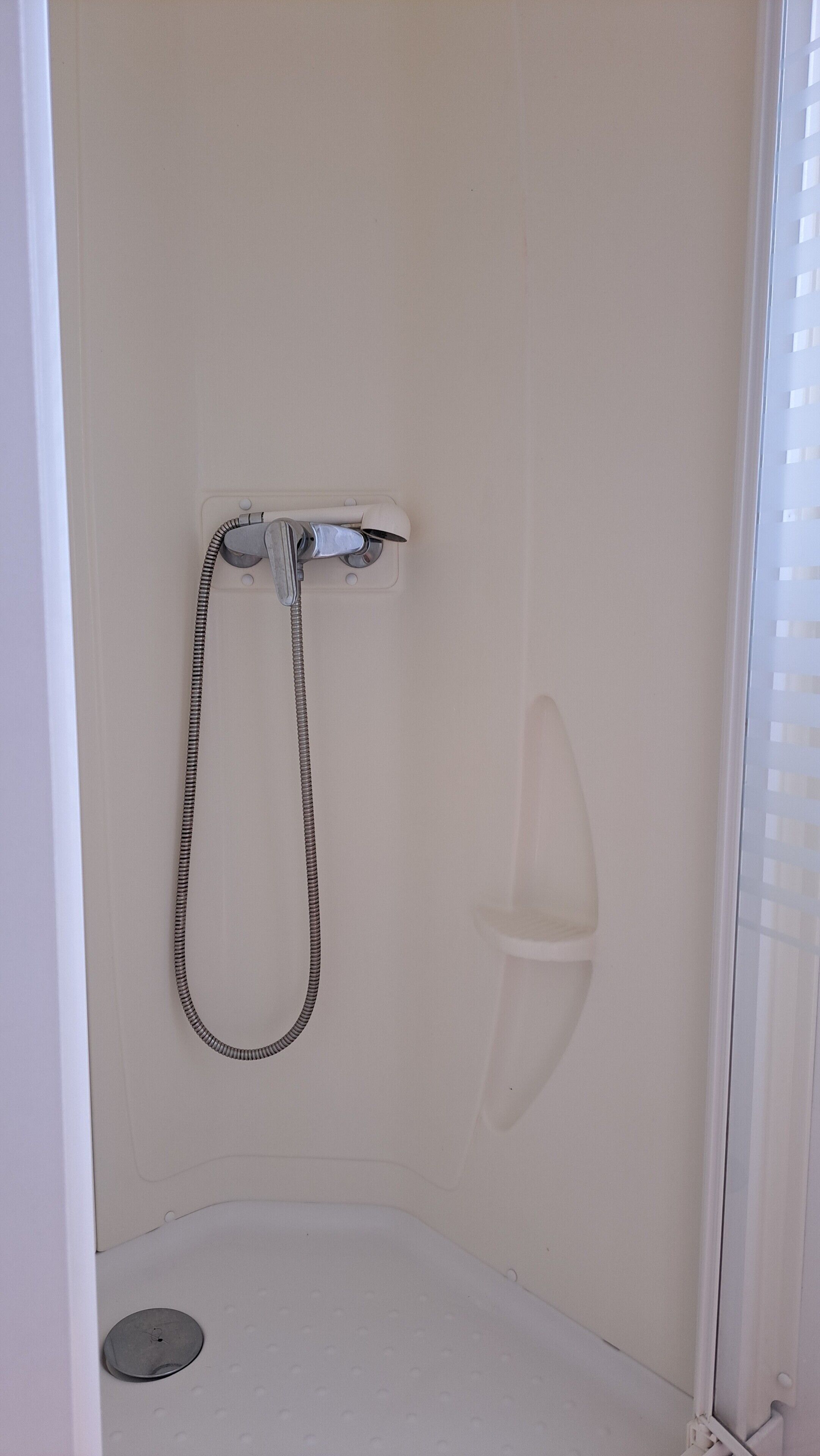 Ducha con manguera, desagüe y panel de control en la pared.