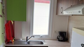 A compact kitchen with a sink, a coffee maker, and a dishwasher. - Chalet 'Bungalow T3 V - 15 Min From Nazaré' with Shared Pool, Private Terrace and Air Conditioning (Pataias)