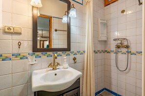 Une salle de bain avec un lavabo, un miroir, une douche et des murs carrelés.