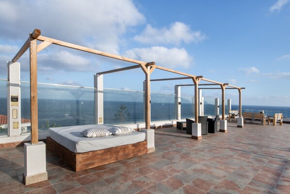 A balcony with a bed, seating area, and a view of the sea. - Holiday Home 'Viento De Sal' with Sea View, Shared Pool and Wi-Fi (Villa de Mazo)