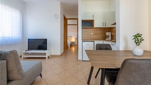 Una sala de estar moderna con un televisor de pantalla plana, un sofá y un comedor con una mesa y sillas.