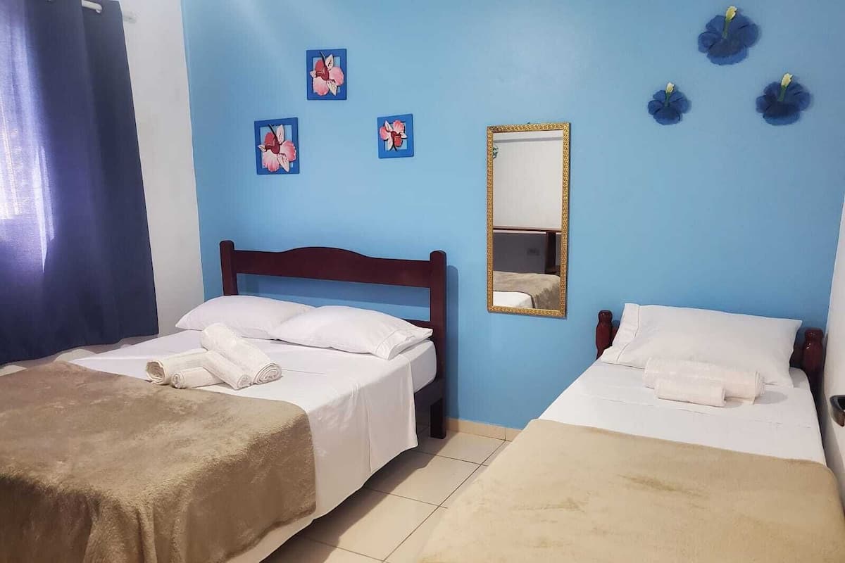 Hotellihuone, jossa on kaksi sänkyä, puinen pääty ja peili sekä taideteos seinällä.