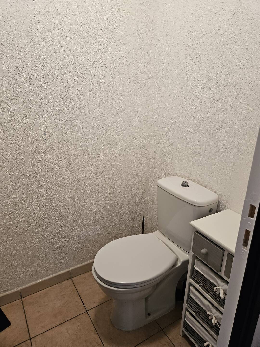 Une petite salle de bain compacte, avec des toilettes blanches, un lavabo blanc et un sol carrelé.