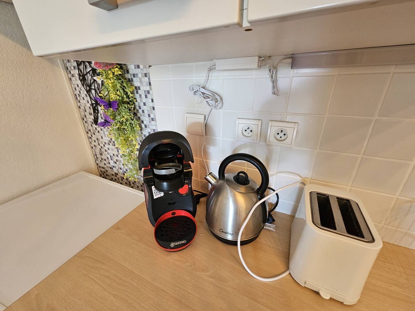 Een keuken met een koffiezetapparaat, waterkoker en broodrooster op het aanrecht.