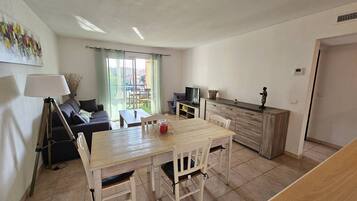 Una sala de estar moderna con una mesa de comedor, sofá y televisor.