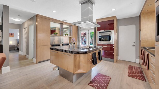 A modern kitchen with a central island, stainless steel appliances, and wooden cabinetry.