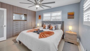 A bedroom with a bed, ceiling fan, bedside tables, and a window.
