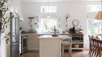 A modern kitchen with white cabinetry, stainless steel appliances, and a central island with stools.