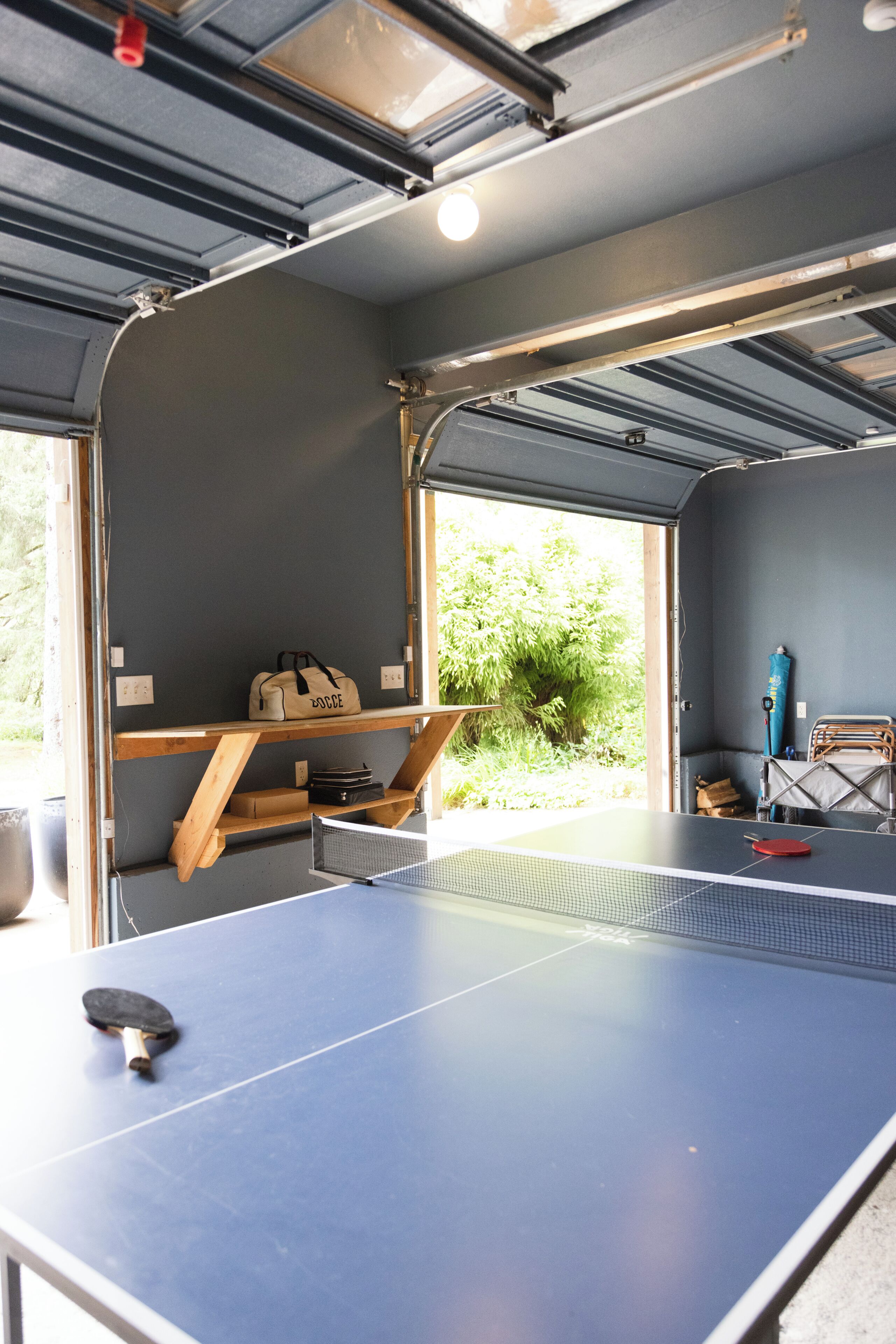 Une table de ping-pong dans une pièce avec une fenêtre, une porte et un banc.