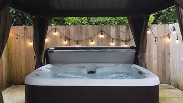 Un jacuzzi con terraza de madera y luces cálidas.
