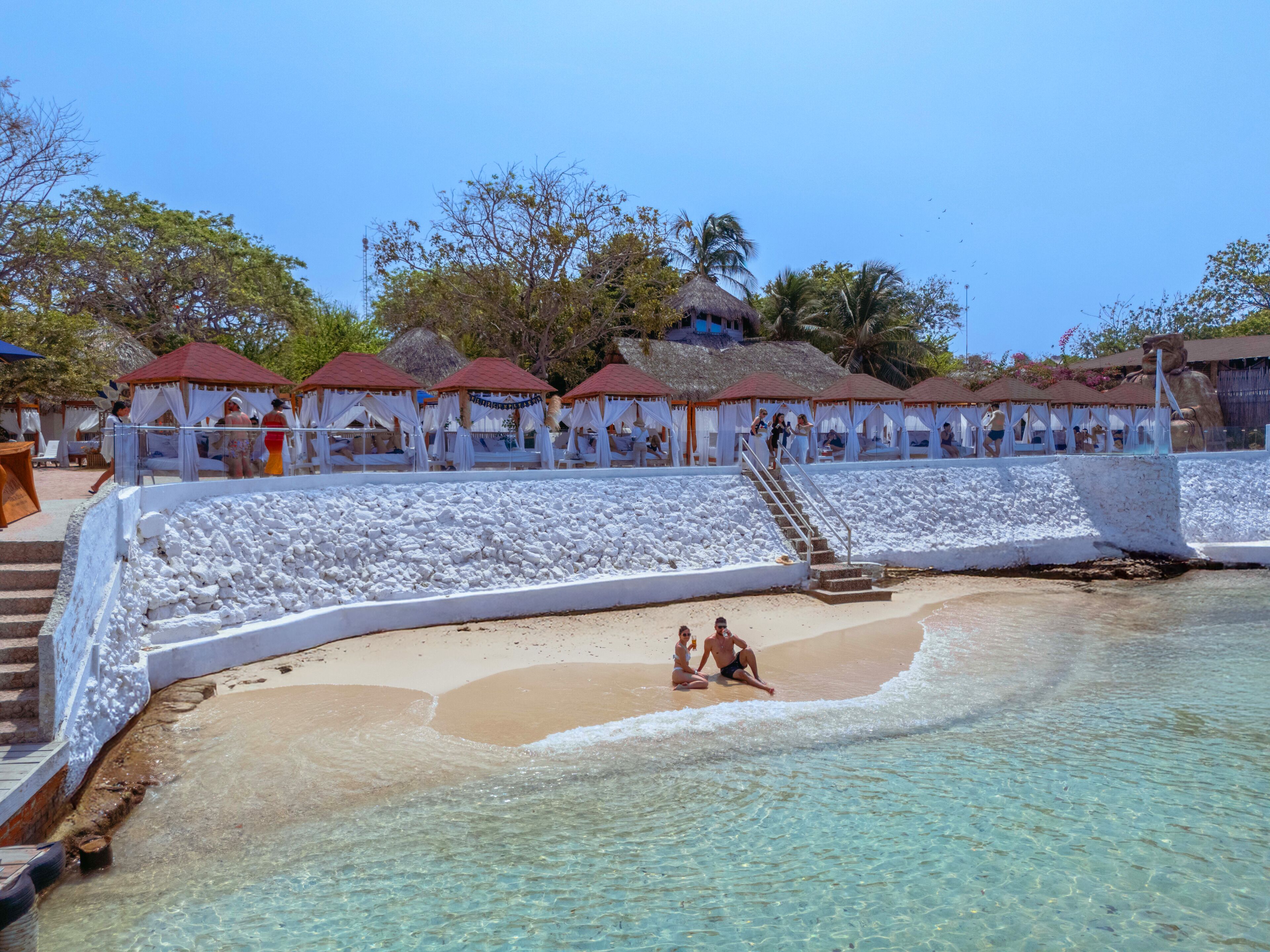 A beach resort with overwater bungalows, clear turquoise water, and a sandy beach.