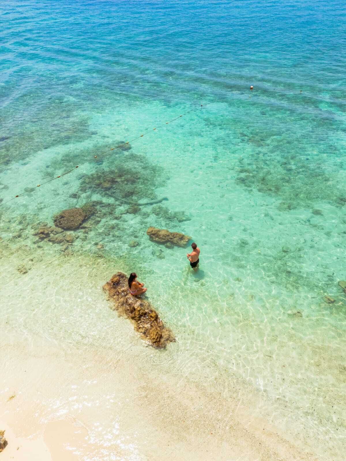 A clear view of a beach with visible rocks and calm water.