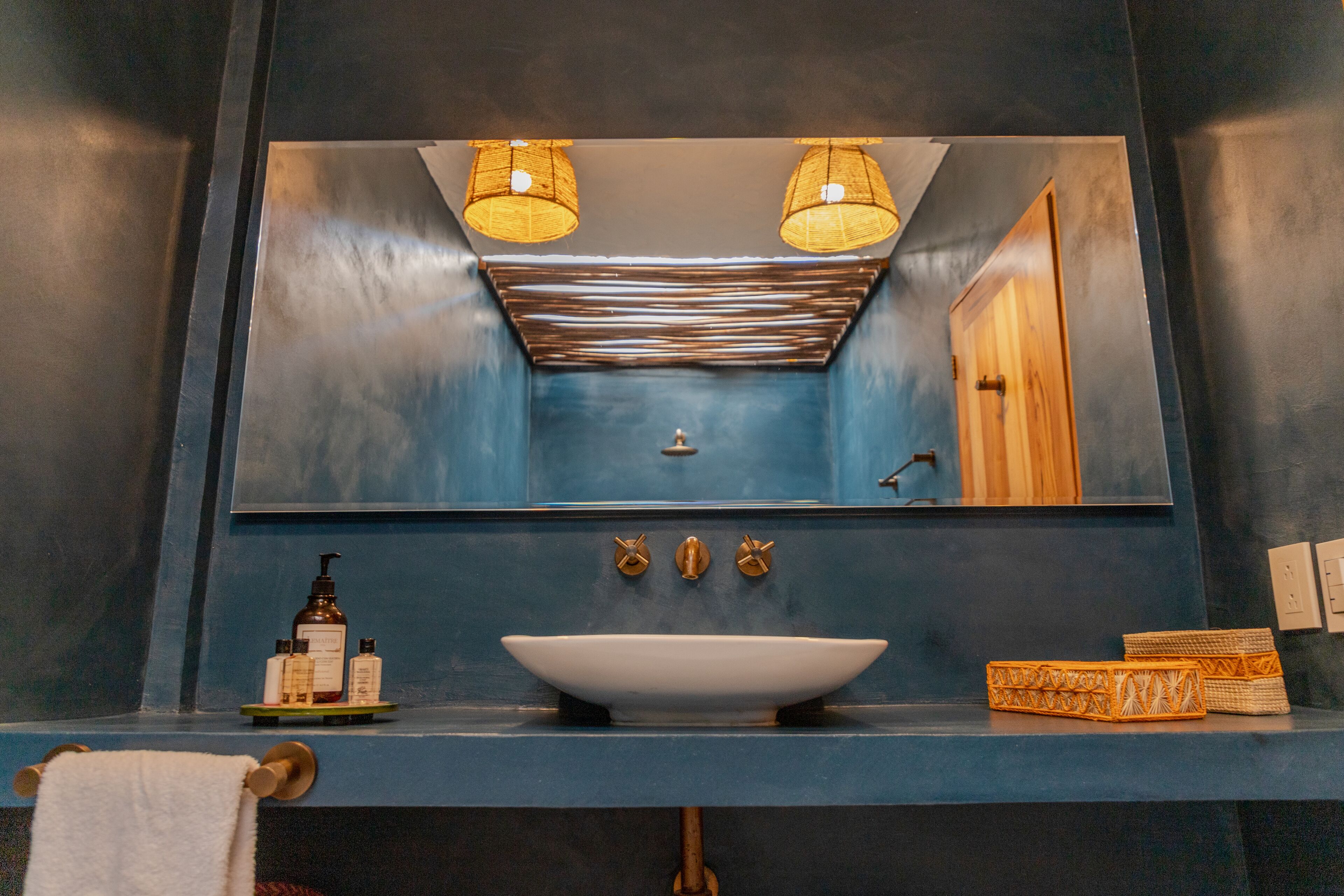 A bathroom with a blue sink, two wall-mounted lights, a mirror, and a towel rack.