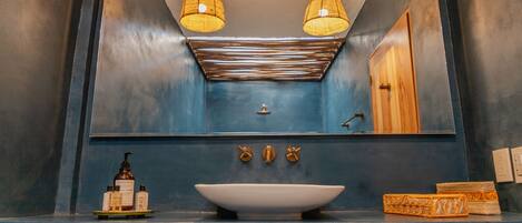 A bathroom with a blue sink, two wall-mounted lights, a mirror, and a towel rack.