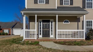A two-story house with a front porch, a garage, and a well-maintained lawn.