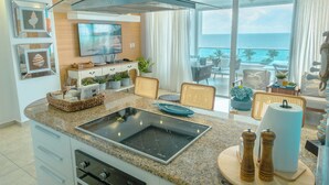 Una cocina moderna con una isla grande, un televisor de pantalla plana y vista al océano.