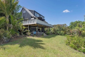 A two-story house with a balcony, surrounded by lush greenery.