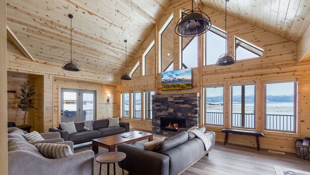 Un salón amplio con chimenea, ventanas grandes y techo alto.